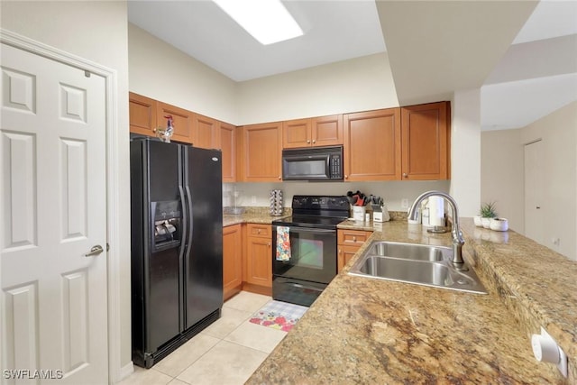 kitchen featuring brown cabinets, light tile patterned floors, a sink, a peninsula, and black appliances