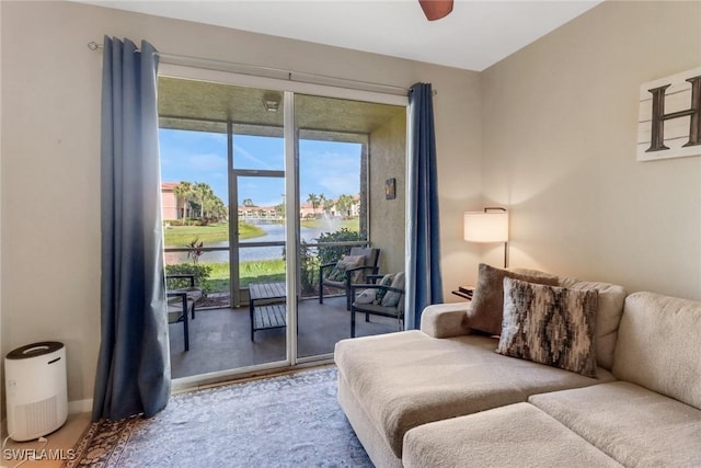 living room featuring a water view, baseboards, and a ceiling fan
