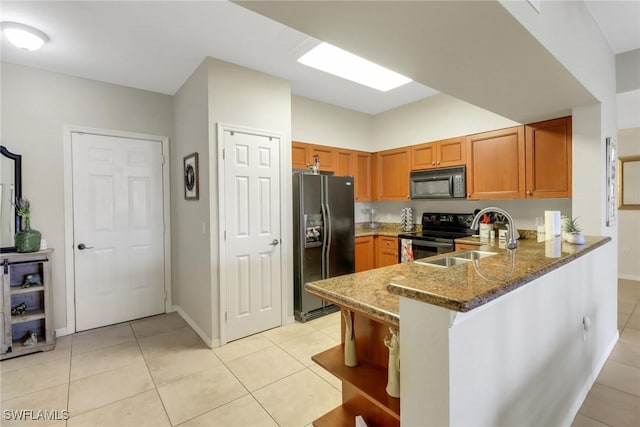 kitchen with stone countertops, light tile patterned flooring, a sink, a peninsula, and black appliances