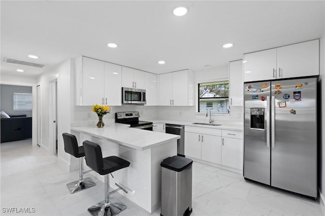 kitchen with visible vents, appliances with stainless steel finishes, a peninsula, marble finish floor, and a sink