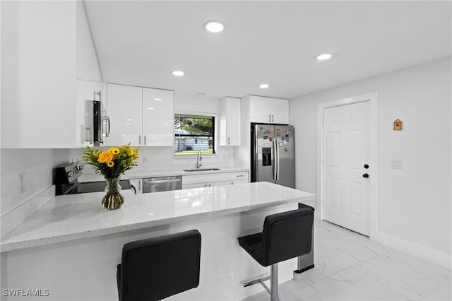 kitchen featuring stainless steel appliances, a peninsula, a sink, marble finish floor, and modern cabinets