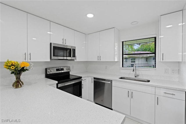 kitchen featuring white cabinetry, stainless steel appliances, a sink, and recessed lighting