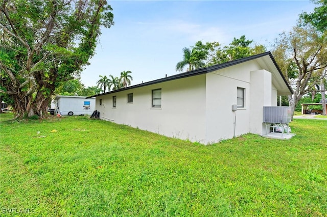 view of side of home with a lawn and stucco siding