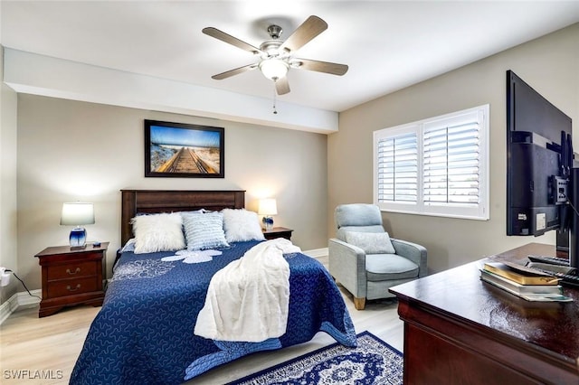 bedroom with ceiling fan, light wood-style flooring, and baseboards