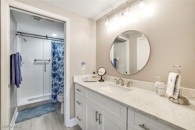 full bath featuring vanity, wood finished floors, a shower stall, and toilet