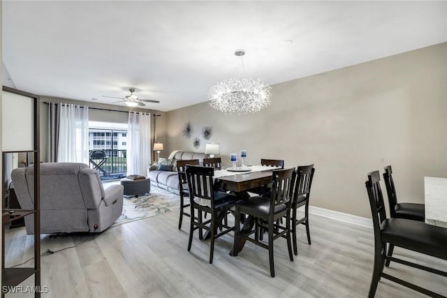 dining space with light wood-style flooring, baseboards, and ceiling fan with notable chandelier