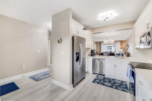 kitchen with stainless steel appliances, a sink, white cabinetry, light countertops, and light wood-type flooring