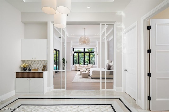 interior space with a chandelier, recessed lighting, a high ceiling, baseboards, and decorative backsplash