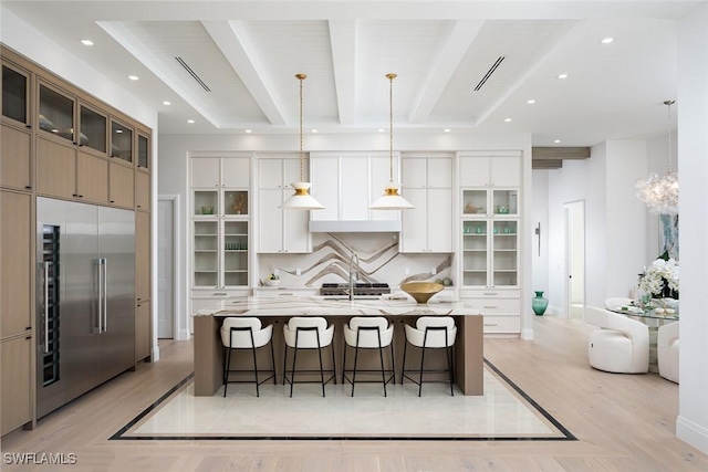 kitchen featuring built in fridge, recessed lighting, backsplash, beam ceiling, and a kitchen bar