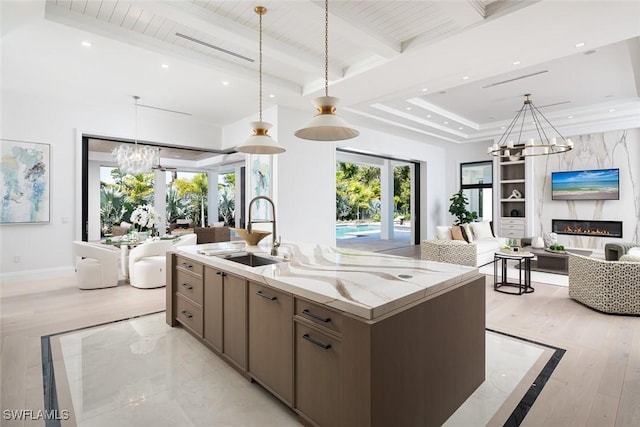 kitchen with a chandelier, open floor plan, a sink, and beam ceiling