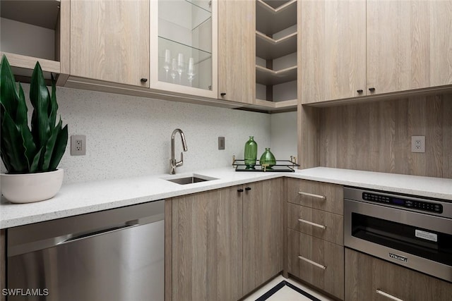 kitchen featuring modern cabinets, appliances with stainless steel finishes, backsplash, and a sink