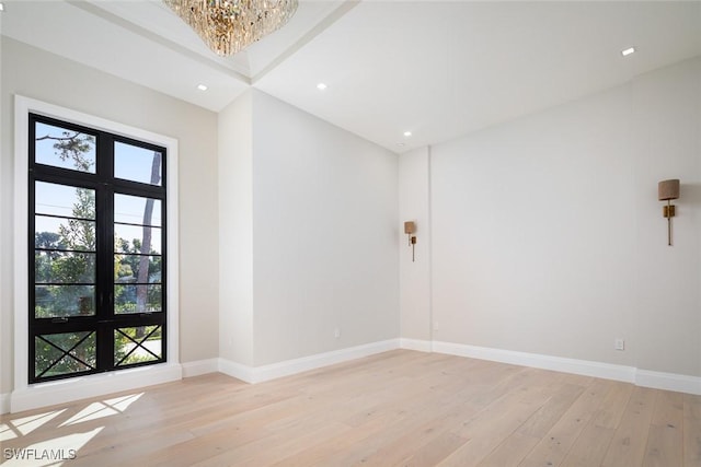 spare room featuring light wood-style floors, baseboards, a notable chandelier, and recessed lighting