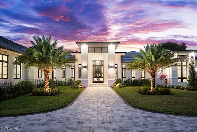 view of front of house featuring a lawn, french doors, and stucco siding