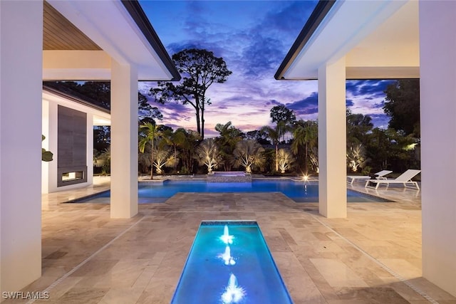 patio terrace at dusk featuring an outdoor pool