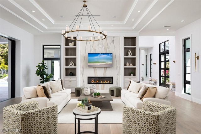 living area featuring plenty of natural light, a tray ceiling, built in features, and wood finished floors