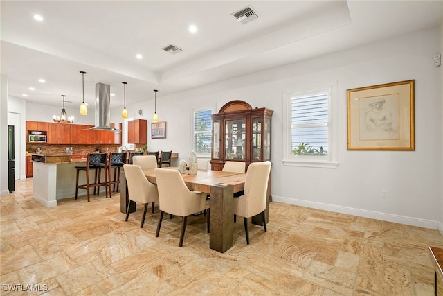 dining room with a healthy amount of sunlight, baseboards, visible vents, and a raised ceiling