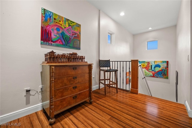 living area with recessed lighting, wood finished floors, an upstairs landing, and baseboards