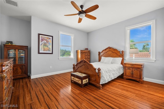 bedroom featuring a ceiling fan, wood finished floors, visible vents, and baseboards