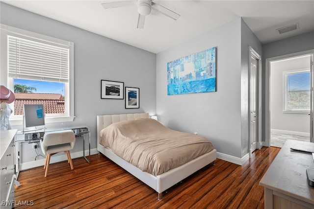 bedroom featuring a ceiling fan, dark wood-style flooring, visible vents, and baseboards