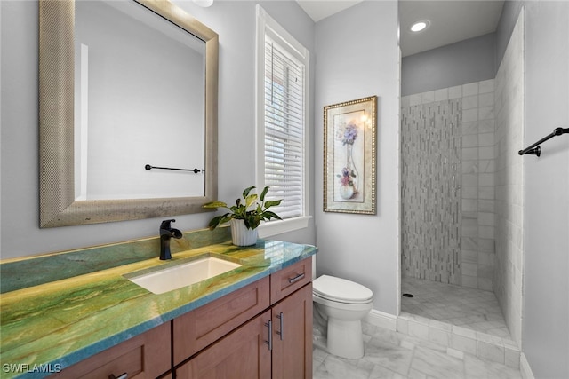 bathroom featuring baseboards, toilet, marble finish floor, a tile shower, and vanity