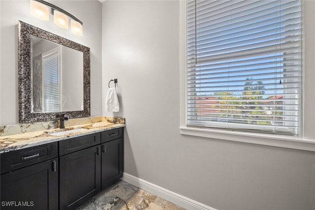 bathroom with stone finish floor, vanity, and baseboards