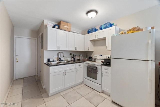 kitchen with light tile patterned flooring, white appliances, a sink, white cabinetry, and dark countertops