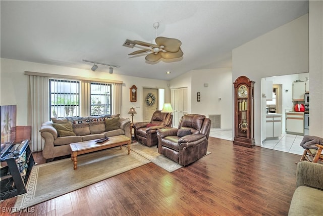 living room with a ceiling fan, light wood-type flooring, visible vents, and vaulted ceiling