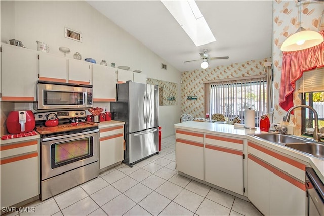 kitchen with vaulted ceiling with skylight, stainless steel appliances, a sink, visible vents, and light countertops