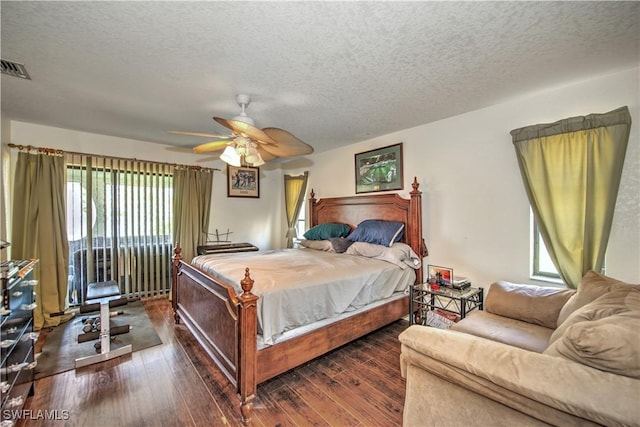 bedroom featuring wood-type flooring, visible vents, ceiling fan, and a textured ceiling