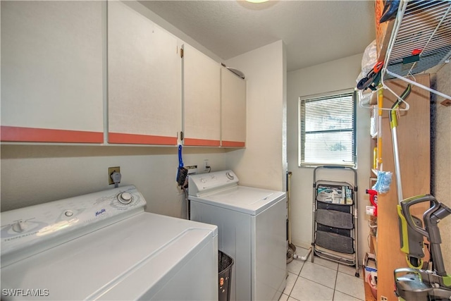 laundry area featuring cabinet space, light tile patterned floors, and washing machine and clothes dryer