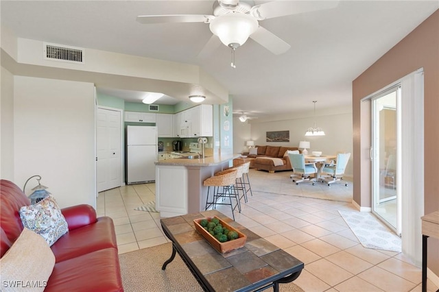 living room with ceiling fan with notable chandelier, visible vents, and light tile patterned flooring