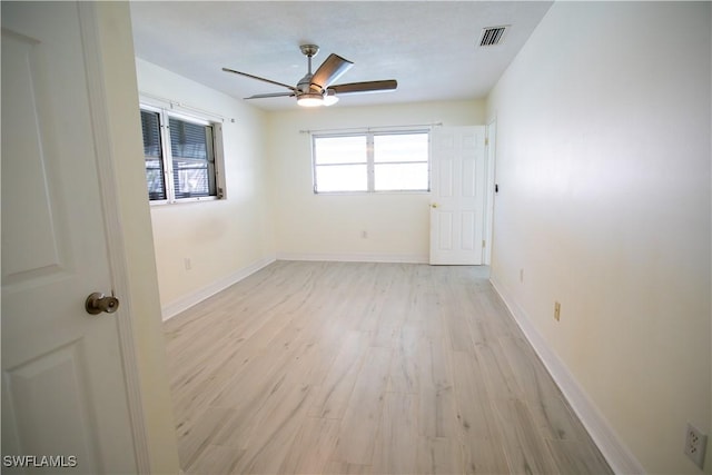 unfurnished room with a ceiling fan, light wood-style flooring, visible vents, and baseboards