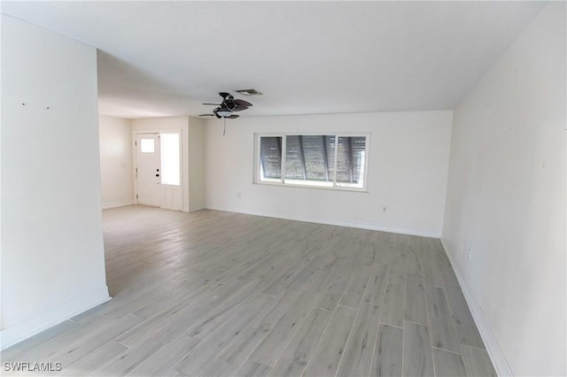 unfurnished room with ceiling fan, light wood-type flooring, visible vents, and baseboards