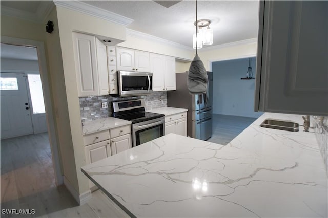 kitchen featuring tasteful backsplash, crown molding, stainless steel appliances, and a sink