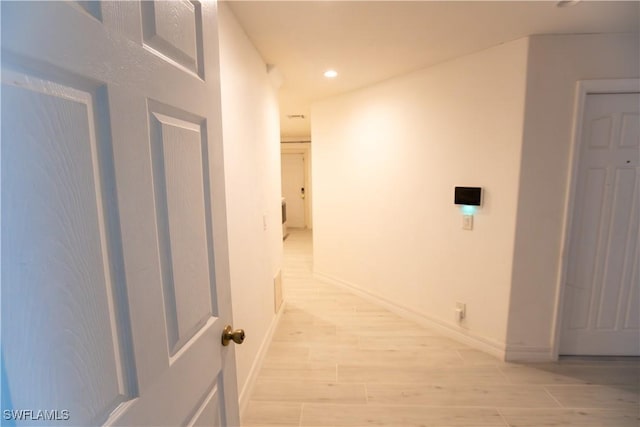 corridor with light wood finished floors, recessed lighting, and baseboards