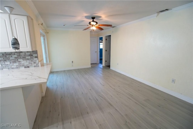 unfurnished living room featuring ceiling fan, light wood-style flooring, visible vents, baseboards, and crown molding