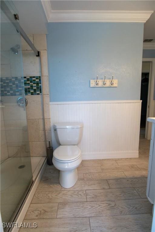 full bath featuring toilet, a wainscoted wall, visible vents, a stall shower, and crown molding