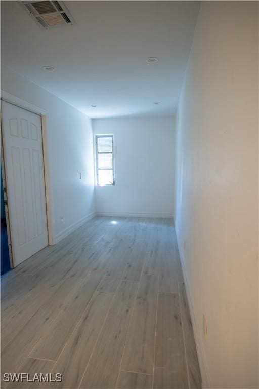 unfurnished room with light wood-style flooring, visible vents, and baseboards