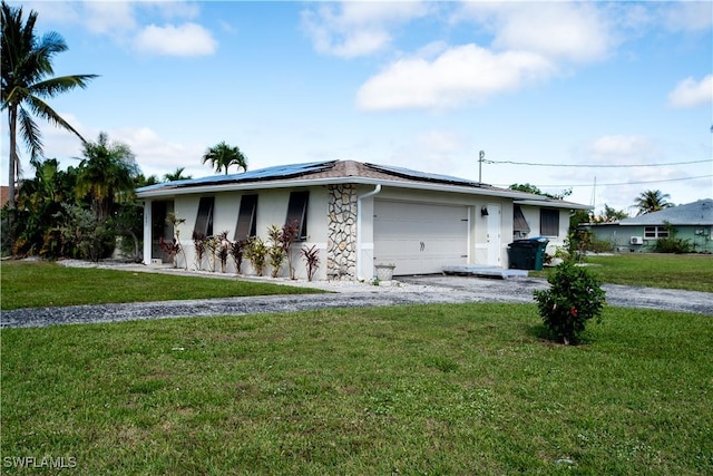 ranch-style house with stucco siding, solar panels, a front yard, a garage, and driveway