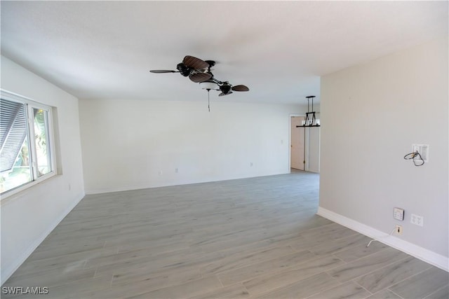 empty room with a ceiling fan, light wood-style flooring, and baseboards