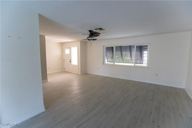 spare room featuring a ceiling fan, visible vents, baseboards, and wood finished floors