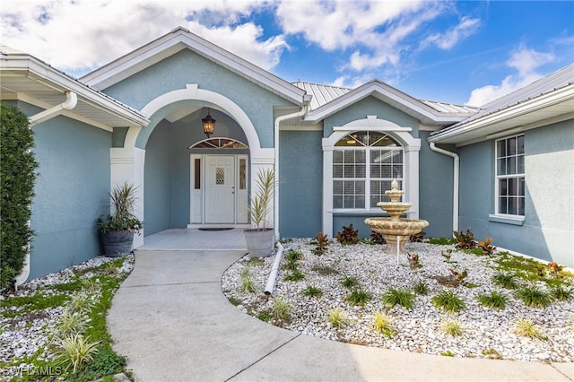 entrance to property featuring metal roof and stucco siding