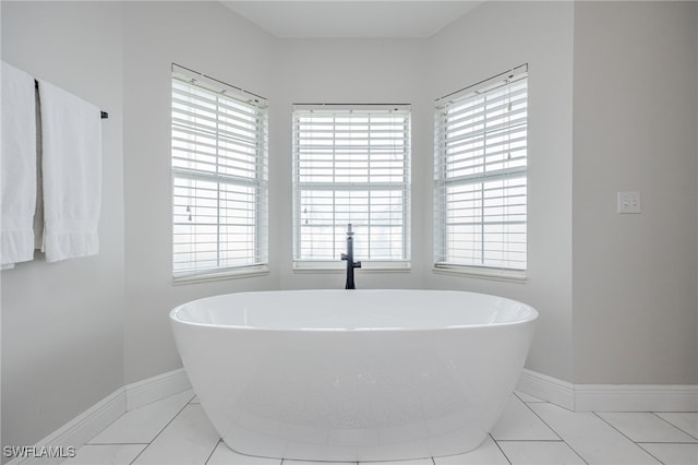 full bathroom featuring baseboards, a soaking tub, and a healthy amount of sunlight