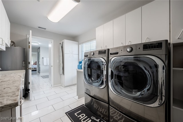 laundry room with cabinet space, washing machine and dryer, light tile patterned floors, and visible vents