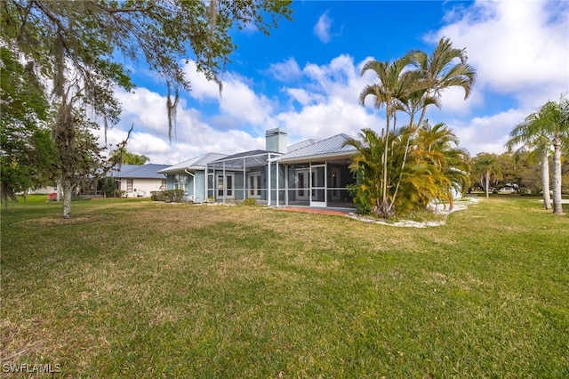 1261 Riverbend Dr, Labelle, FL 33935 - back of house with a chimney, a lawn, a sunroom, and metal roof