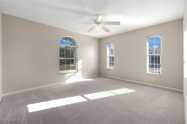 carpeted spare room with ceiling fan and baseboards