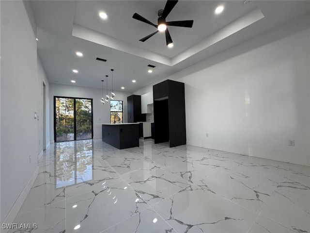 unfurnished living room featuring a raised ceiling, visible vents, a sink, and marble finish floor