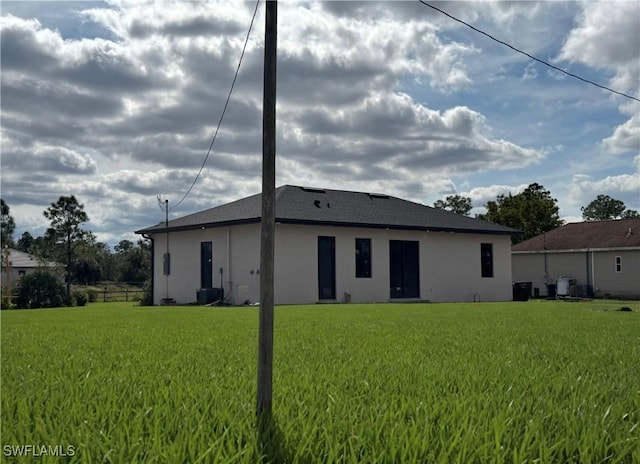 back of house with a yard and stucco siding