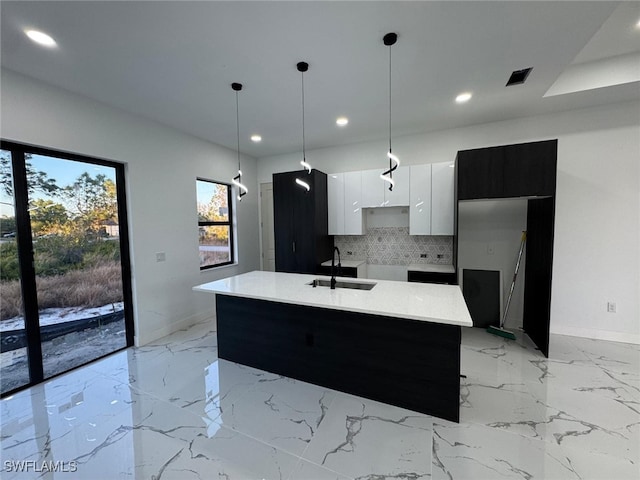 kitchen with a kitchen island with sink, white cabinets, light countertops, modern cabinets, and pendant lighting