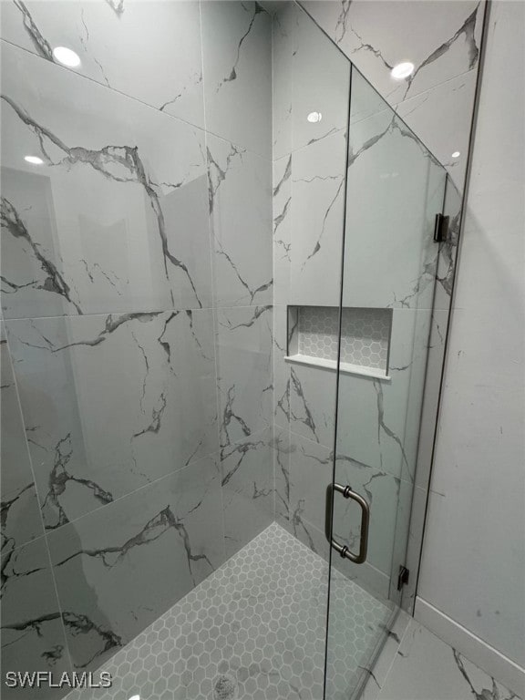 bathroom featuring marble finish floor and a stall shower